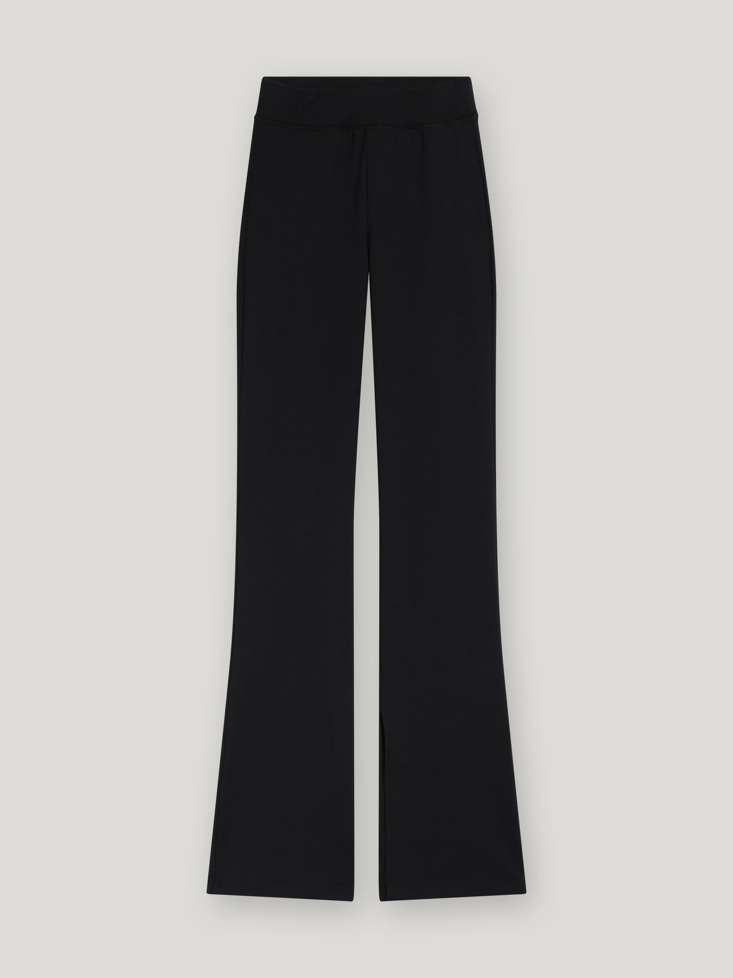 Leggings mit Schlitzen - 80% Recycled in Schwarz, mit hoher Taille, weitem Bein und dezenten Schlitzen am vorderen Saum, hergestellt aus recyceltem Polyester und flach auf hellgrauem Hintergrund.