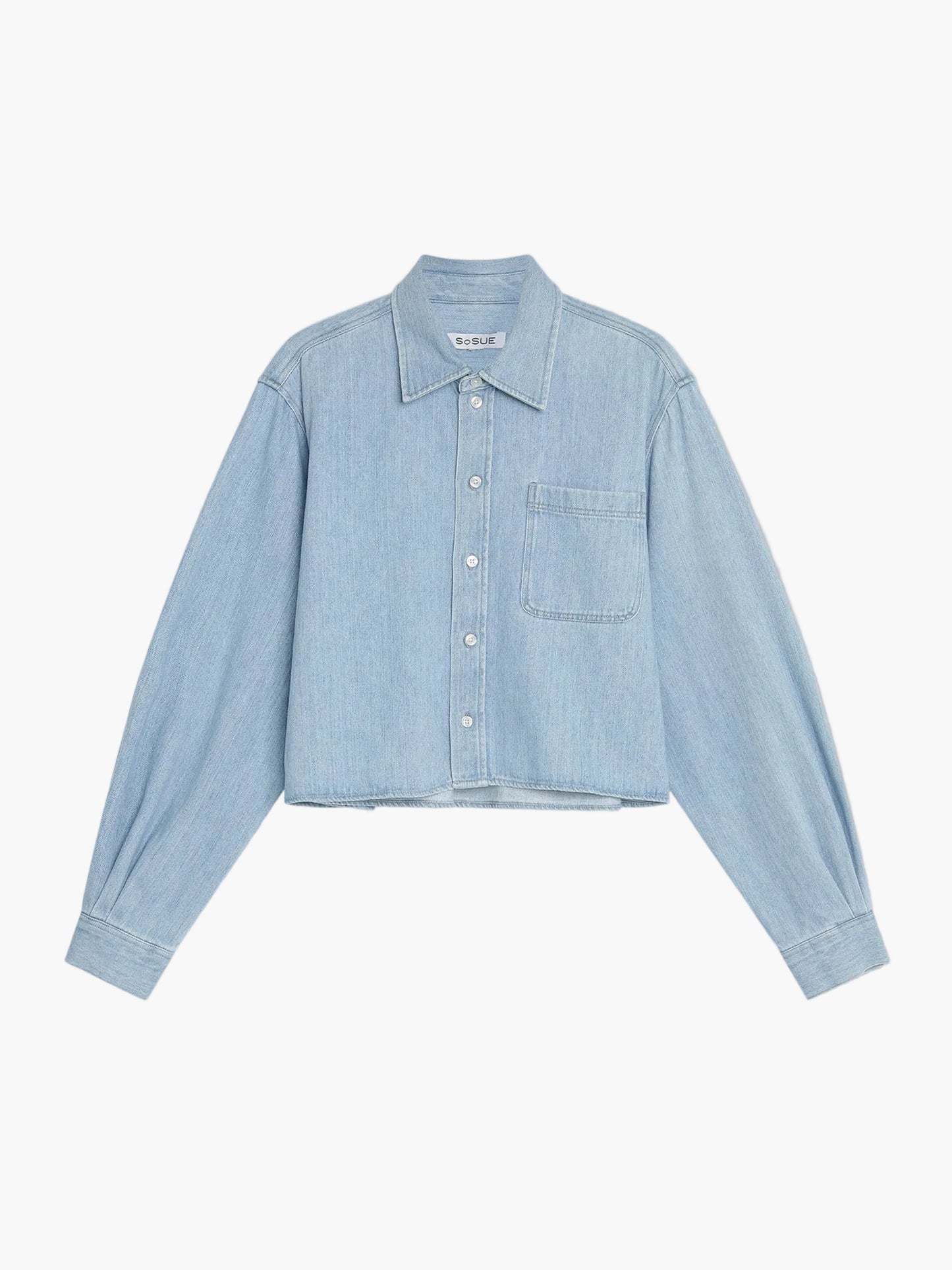 Die Bluse Denim Cropped ist hellblau und hat lange Ärmel, einen Kragen, eine einzelne Brusttasche und einen verkürzten Saum. Sichtbare weiße Nähte und silberne Knöpfe verleihen dieser stilvollen, modernen kurzen Bluse Damen ihren unverwechselbaren Look.