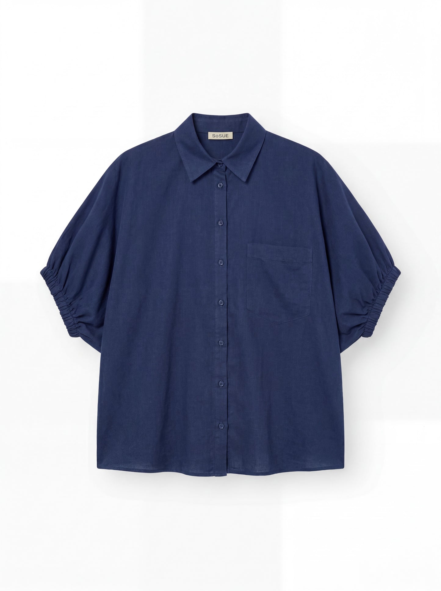 Das Cowboy Collar Voile Navy ist ein locker sitzendes, kurzärmeliges, marineblaues Button-up-Hemd mit einer einzigen Brusttasche und gerafften Ärmeln, das auf einem einfarbig weißen Hintergrund abgebildet ist.