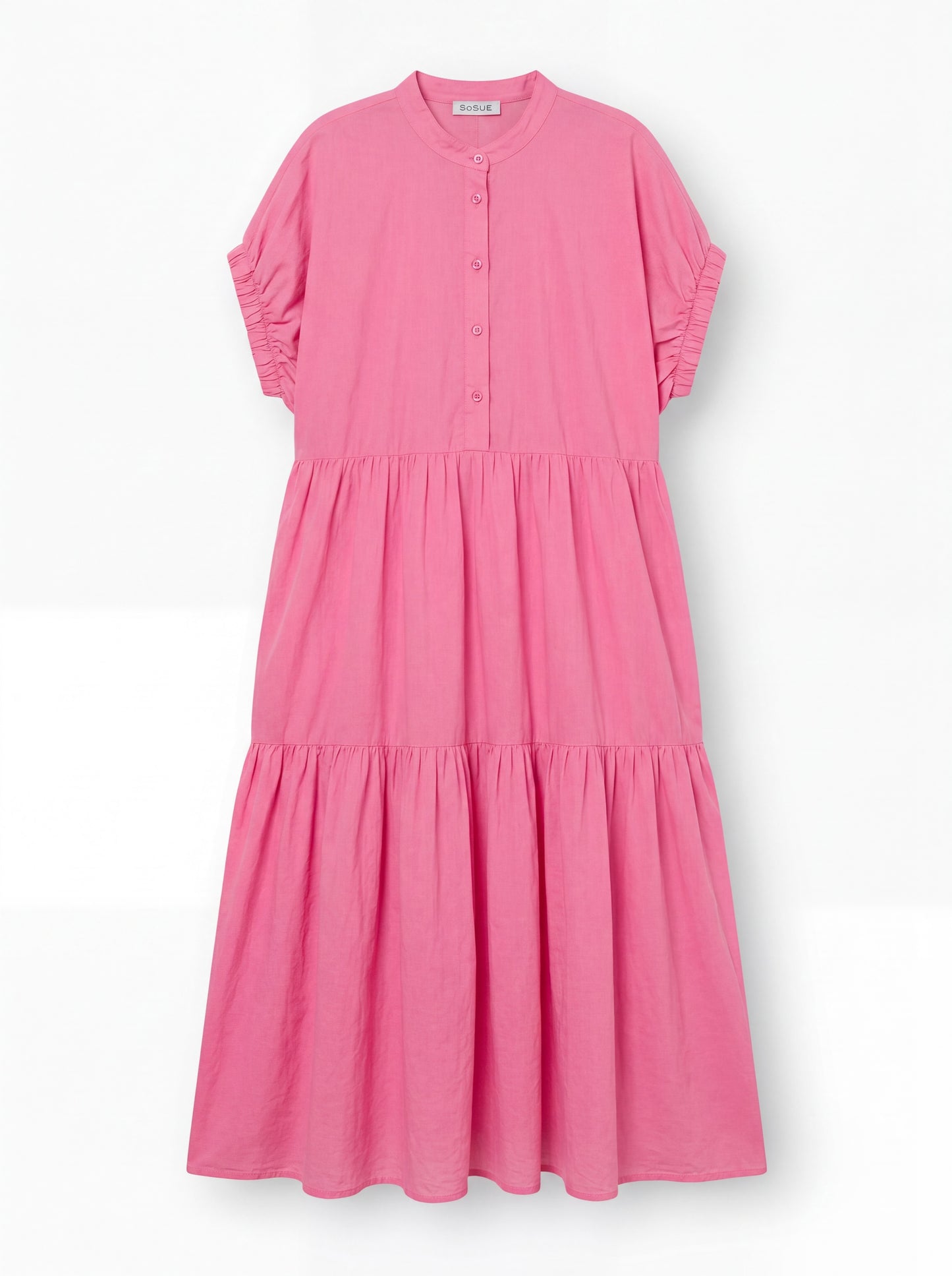 Das Kleid Cowboy Boho Pink ist ein locker sitzendes, knöchellanges Baumwoll-Voile-Kleid mit kurzen Rüschenärmeln, einem geknöpften Ausschnitt und einem gestuften, gerafften Rock, das auf einem einfarbig weißen Hintergrund abgebildet ist.