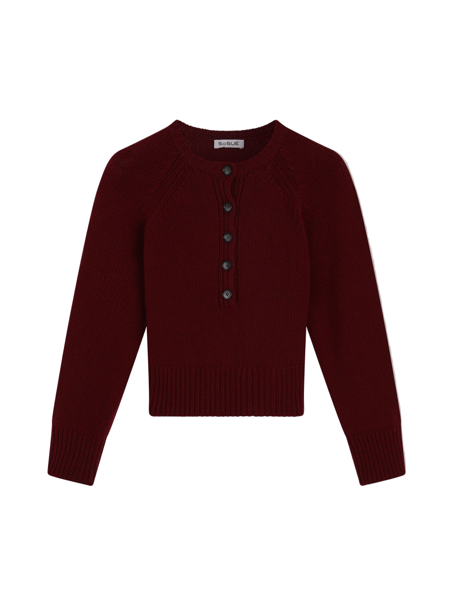 Der Pullover Raglan Burgundy ist ein langärmeliger Damenpullover aus Merinowolle in Dunkelrot. Er hat einen Rundhalsausschnitt, gerippte Bündchen und einen gerippten Saum sowie eine Knopfleiste mit fünf dunklen Knöpfen.