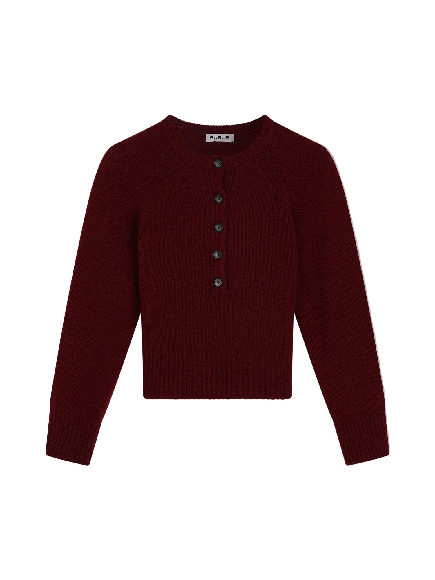 Der Pullover Raglan Burgundy ist ein langärmeliger Damenpullover aus Merinowolle in Dunkelrot. Er hat einen Rundhalsausschnitt, gerippte Bündchen und einen gerippten Saum sowie eine Knopfleiste mit fünf dunklen Knöpfen.