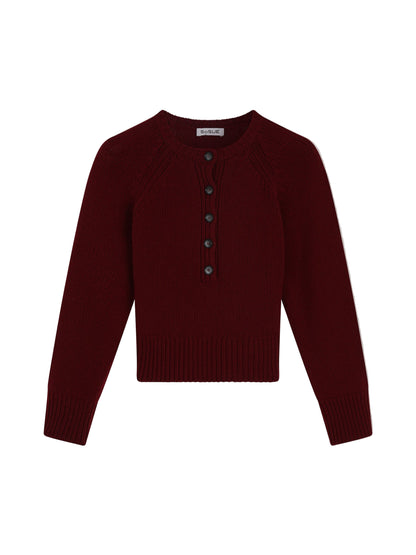 Der Pullover Raglan Burgundy ist ein langärmeliger Damenpullover aus Merinowolle in Dunkelrot. Er hat einen Rundhalsausschnitt, gerippte Bündchen und einen gerippten Saum sowie eine Knopfleiste mit fünf dunklen Knöpfen.
