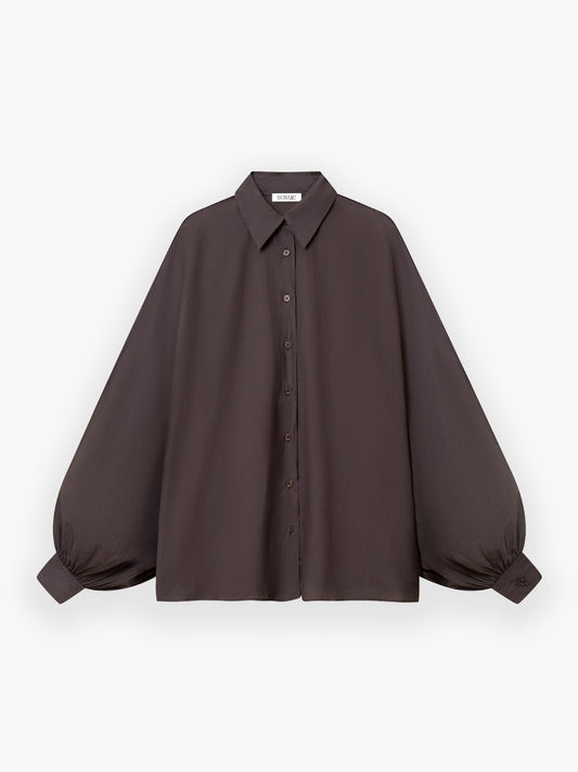 Die Bluse Antonia Voile Brown hat einen spitzen Kragen, eine geknöpfte Vorderseite und voluminöse Ballonärmel mit gerafften Manschetten. Dieses elegante Oberteil in Einheitsgröße ist in Dunkelbraun auf einem schlichten weißen Hintergrund gehalten - perfekt für jeden Anlass.