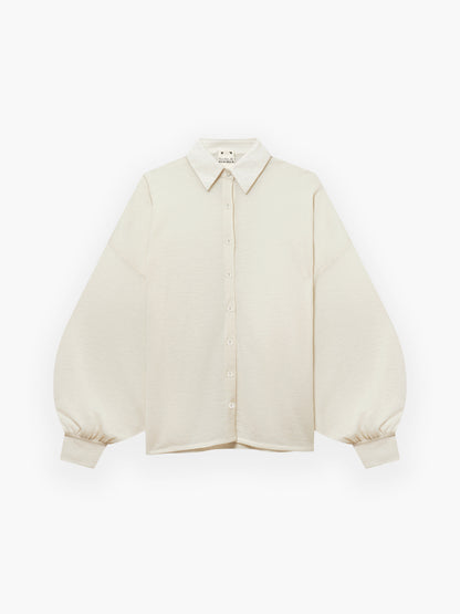 Das Bluse Antonia Cashmere Ecru One Size von Ella Silla x SOSUE ist ein cremefarbenes, langärmeliges Oberteil mit spitzem Kragen und weiten, leicht gepufften Ärmeln, die an den Manschetten gerafft sind, auf einem schlichten weißen Hintergrund.