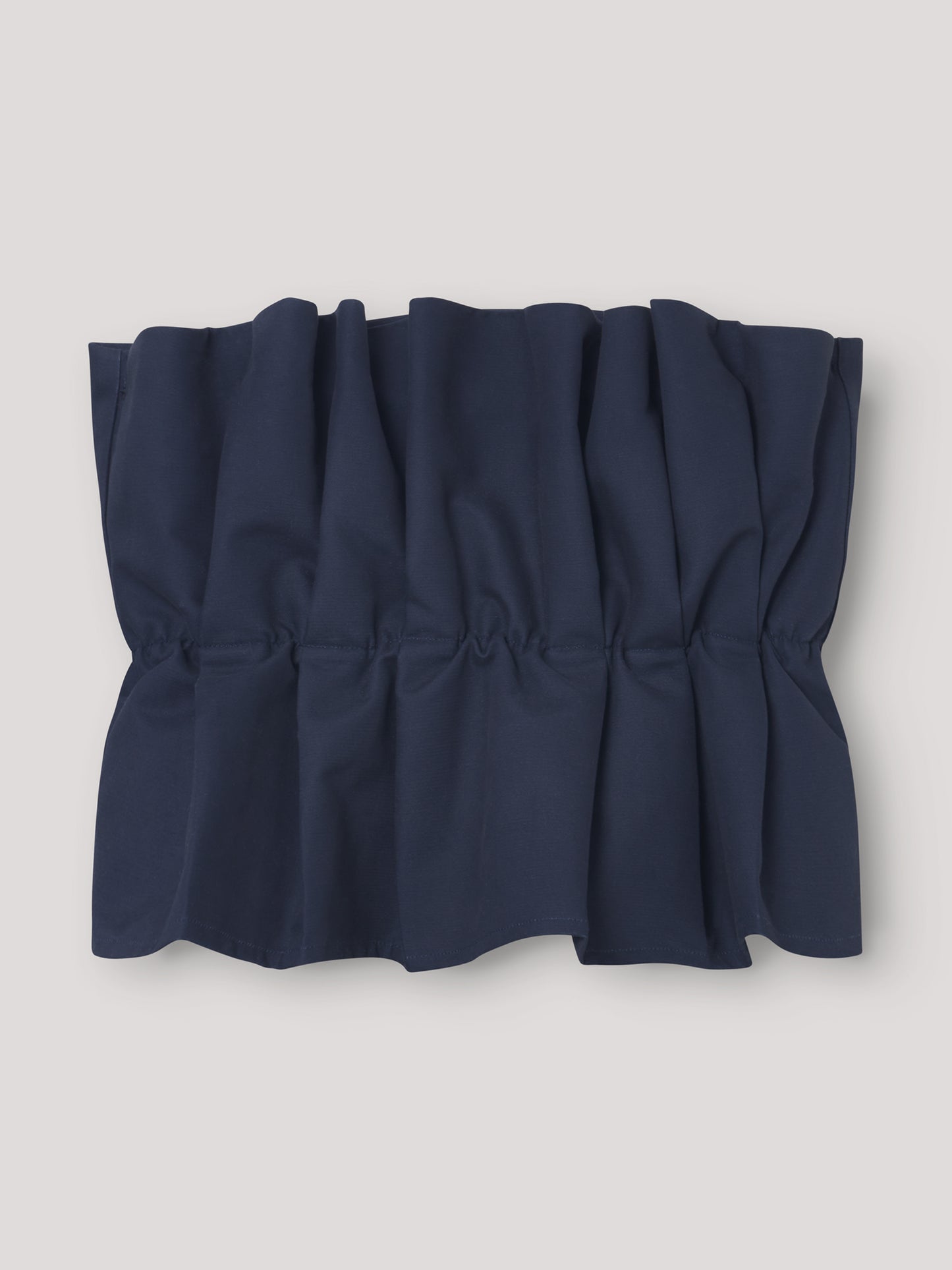 Das Pleat Top Navy, ein schulterfreies Oberteil mit gerafften, gerüschten Details, wird flach auf einem hellen Hintergrund gezeigt.