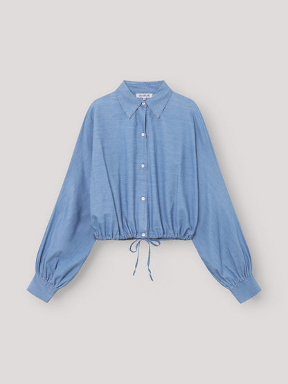 Die Bluse Antonia Drawstring Denim ist eine hellblaue, langärmelige Bluse mit Kragen, elastischen Bündchen und einer lockeren Passform. Der Kordelzug am Saum verleiht dieser stylischen Damenbluse im Denim-Look einen lässigen Touch.