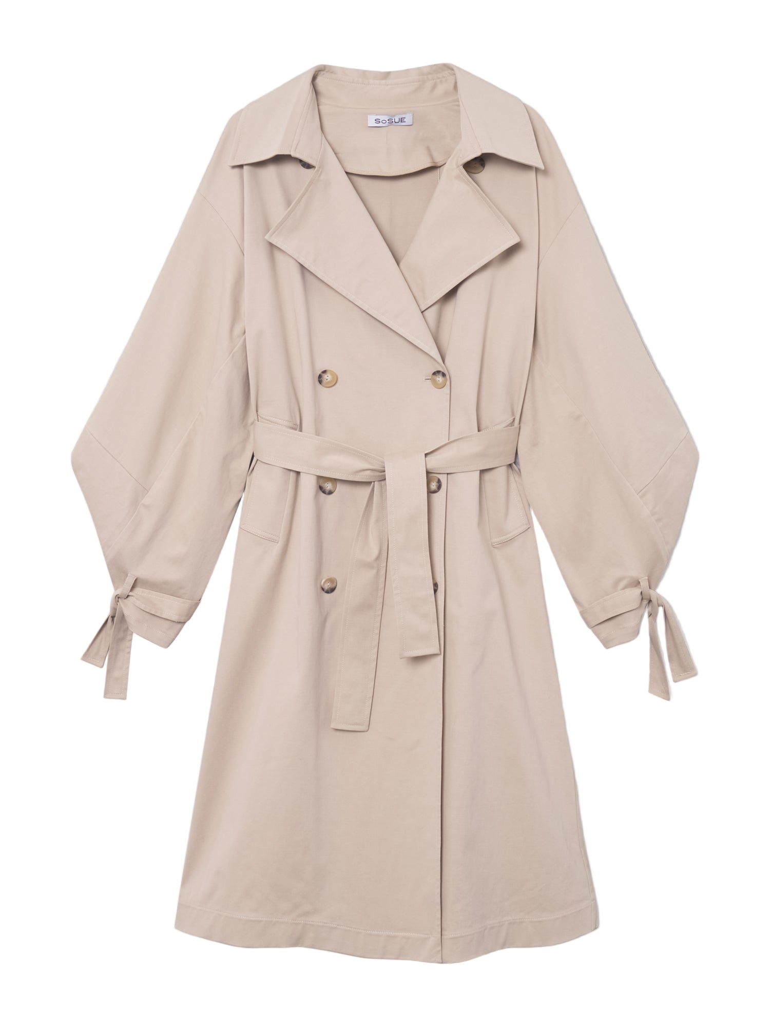 Der Trench Antonia ist ein beigefarbener, knielanger Trenchcoat in Übergröße mit gekerbtem Kragen, doppelreihiger Vorderseite, passendem Gürtel, Knopfdetails und langen Ärmeln mit Manschettenbändern. Er wird vor einem schlichten weißen Hintergrund präsentiert.