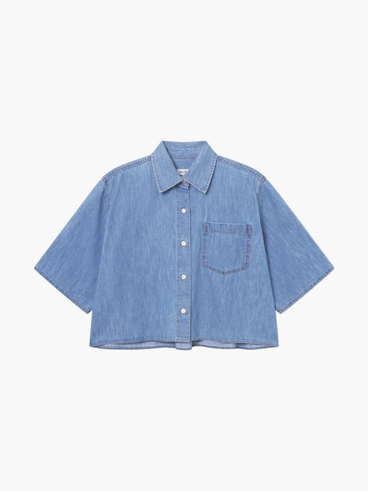 Die Bluse Short Sleeve Denim ist ein hellblaues, kurzärmeliges Denim-Top mit Brusttasche und klassischem Kragen, perfekt als Damenbluse Blau. Diese kurz geschnittene Jeansbluse hebt sich auf einem schlichten weißen Hintergrund ab und sorgt für einen frischen, modernen Stil.