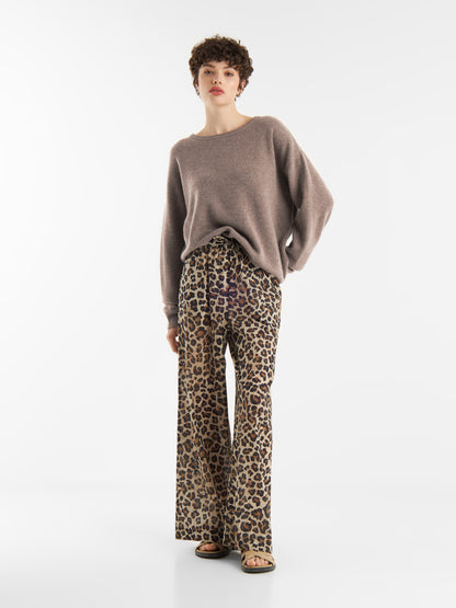 Eine Frau in einem Pullover Boyfriend azteco mit einem Rundhalsausschnitt und einer Hose mit Leopardenmuster.