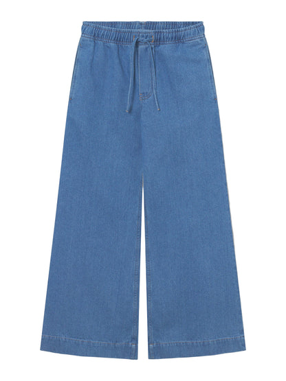 Die Pants Anna Blue hat ein weites Bein, eine lockere Passform mit elastischem Bund, Kordelzug und zwei Seitentaschen. Diese Damenhose aus Denim in Jeansoptik ist flach auf weißem Grund abgebildet.