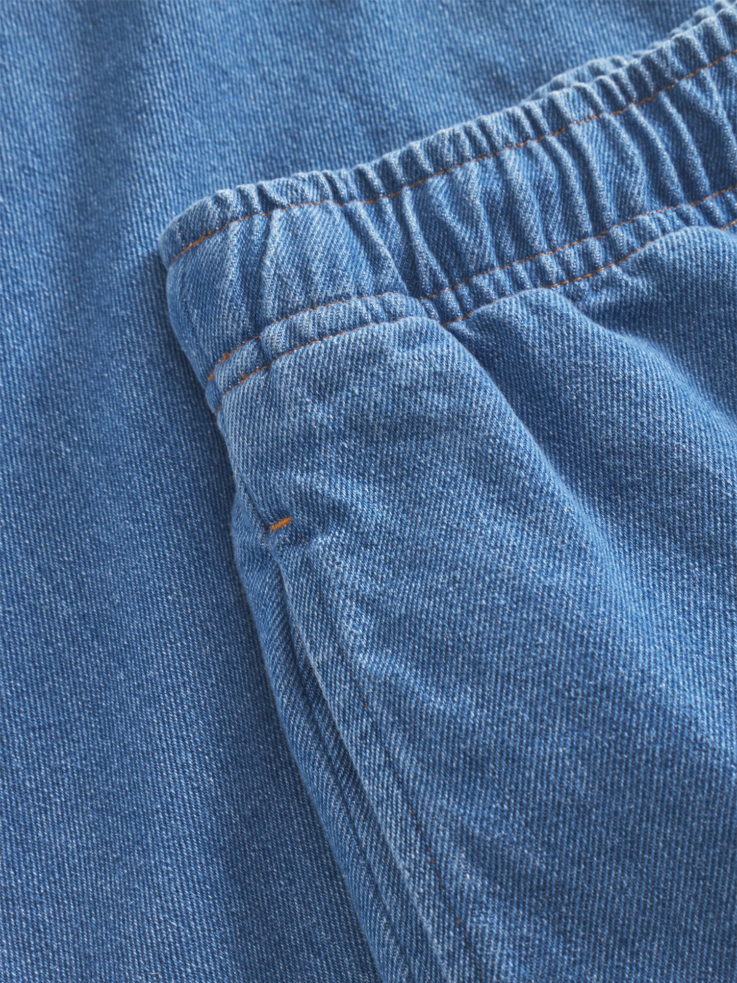 Die Nahaufnahme des Jeansstoffs der Pants Anna Blue zeigt den elastischen Bund, die Tasche, die sichtbaren Nähte, die strukturierten Details und die trendige Jeansoptik.