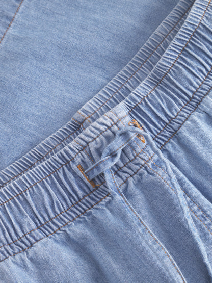 Nahaufnahme der Shorts Light Denim mit elastischem Bund mit Kordelzug, sichtbaren Nähten und gerafftem Stoff.