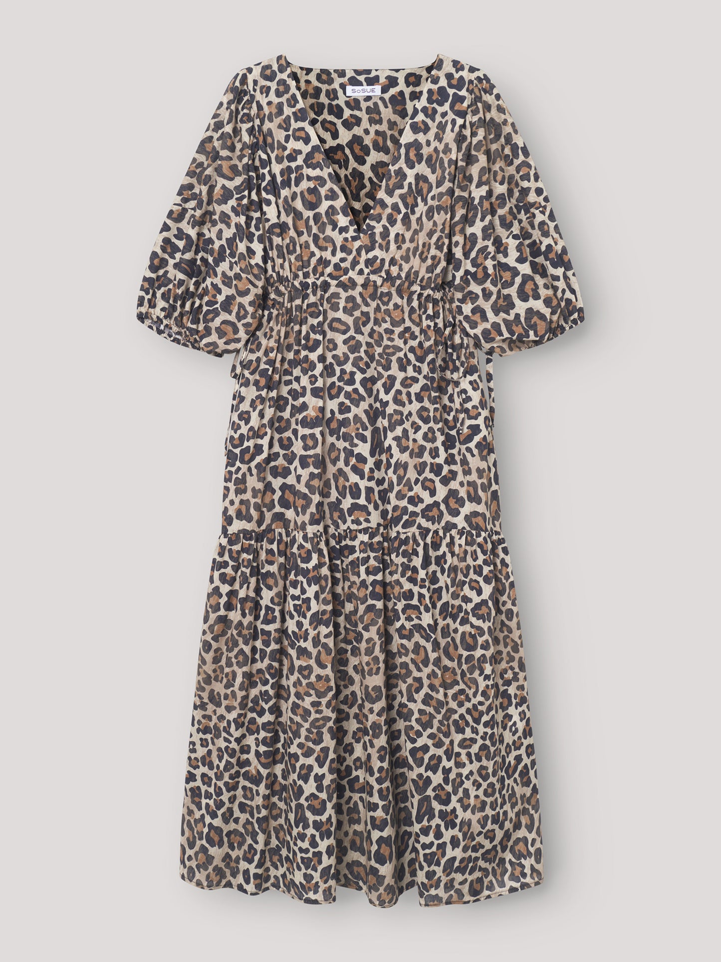 Das Kleid Fleur Leo ist ein stilvolles Maxikleid mit einem auffälligen Leo-Print, kurzen Puffärmeln, einem V-Ausschnitt, einer taillierten Passform und einem gestuften, fließenden Rockteil.