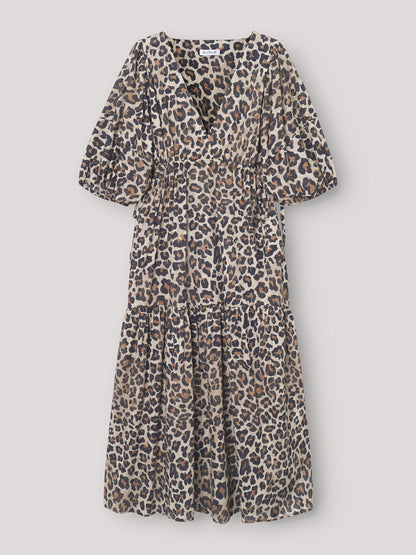 Das Kleid Fleur Leo ist ein stilvolles Maxikleid mit einem auffälligen Leo-Print, kurzen Puffärmeln, einem V-Ausschnitt, einer taillierten Passform und einem gestuften, fließenden Rockteil.