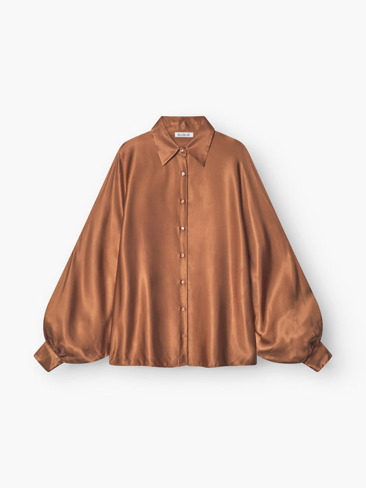 Die Bluse Antonia Shiny Brown ist eine seidige, langärmelige Bluse mit spitzem Kragen, geknöpfter Vorderseite und weiten, gerafften Ärmeln im satinbraunen Damen-Stil, abgebildet auf weißem Hintergrund.