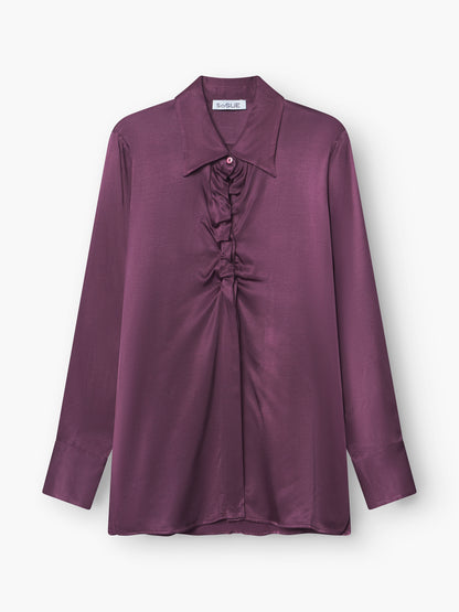 Die Bluse Ella Shiny Purple ist eine langärmelige Satinbluse mit breitem Kragen und gerafften Rüschen in der vorderen Mitte, die auf weißem Hintergrund zu sehen ist.
