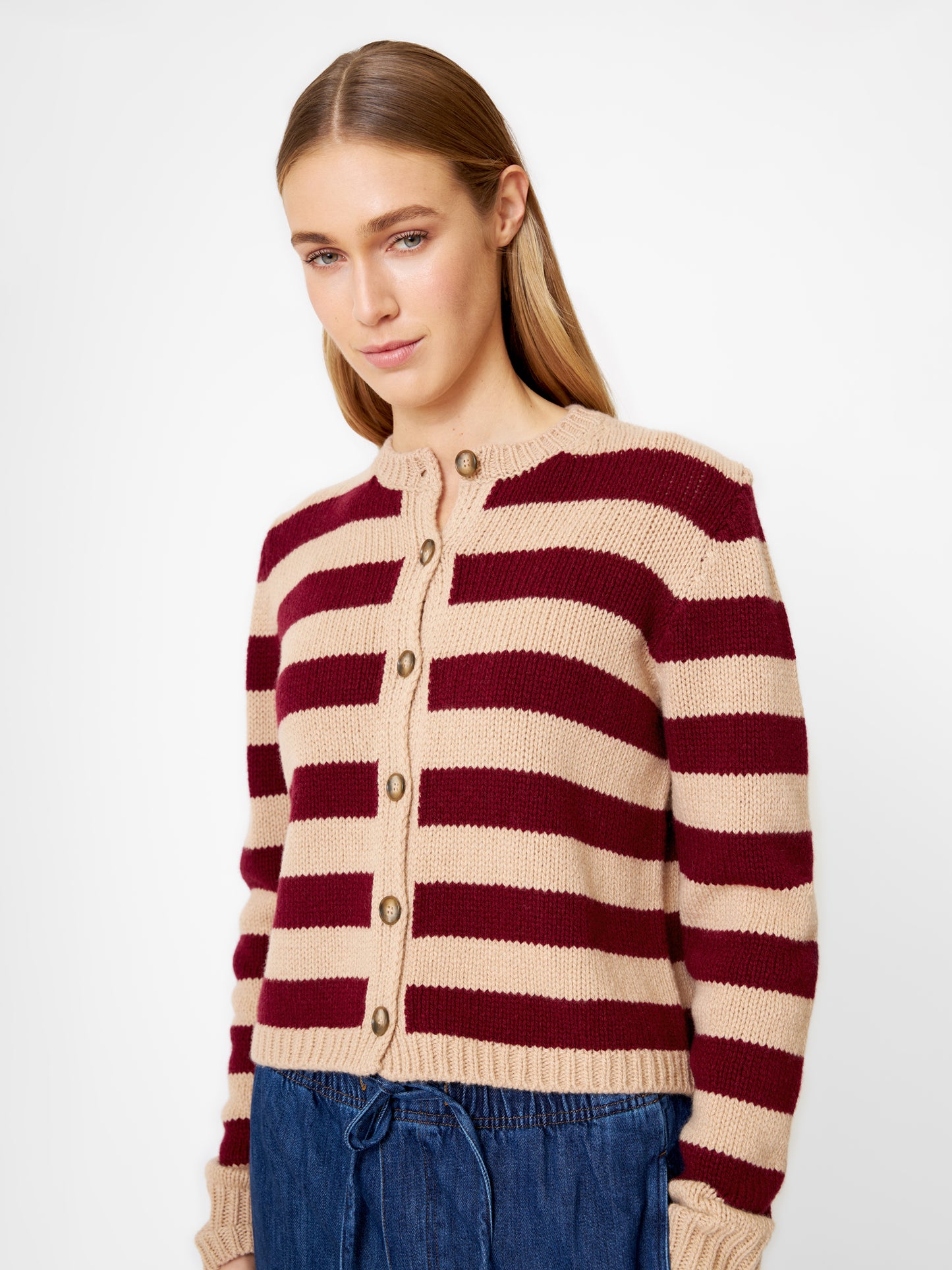 Eine Frau mit glattem, hellbraunem Haar trägt die Jacke Stripe Burgundy Stripe und eine blaue Hose mit Kordelzug und steht vor einem schlichten weißen Hintergrund.