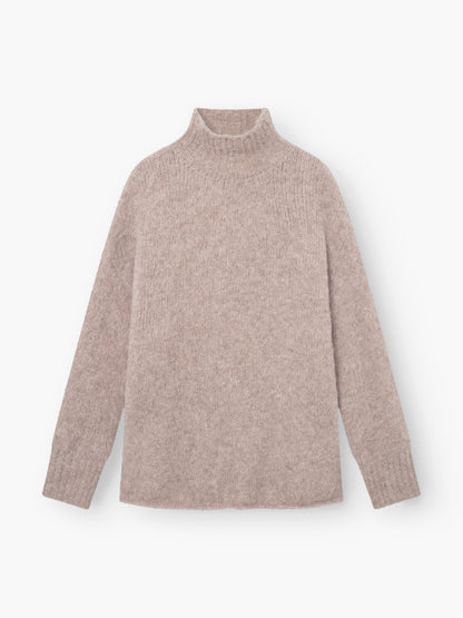 Der Pullover Liv Turtle Beige ist ein hellbeiger Rollkragenpullover mit langen Ärmeln, weicher, flauschiger Textur und gerippten Bündchen und Halsausschnitt, der flach auf weißem Grund liegt und einen gemütlichen Look bietet.