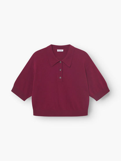 Ein weinrotes Pullover-Polo für Damen mit kurzen Ärmeln, breitem Kragen und Drei-Knopf-Knopfleiste, flach auf weißem Grund abgebildet.