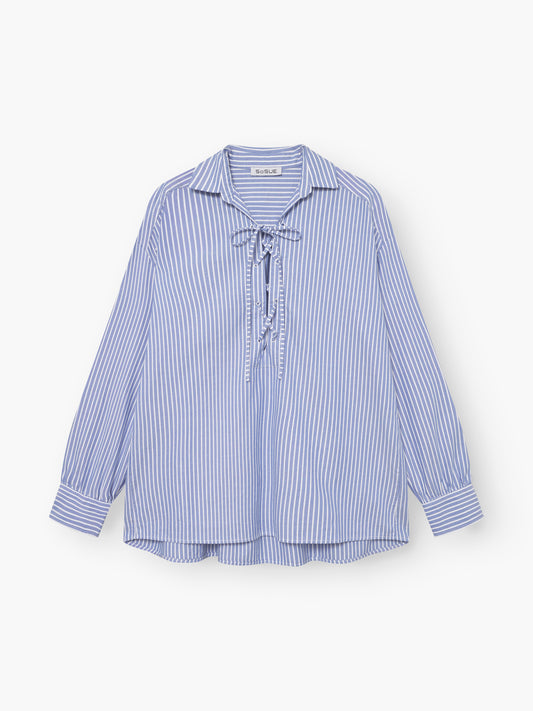 Die Bluse Fisherman Light Blue Stripes hat blaue und weiße Längsstreifen, einen Kragen, eine Schnürung vorne und lange Ärmel. Es besteht aus 100% Baumwolle und ist auf einem weißen Hintergrund abgebildet.