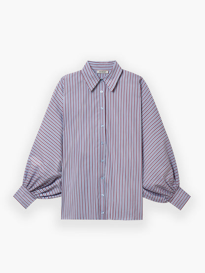 Die Bluse Antonia Blue Burgundy Stripe zeigt rote, blaue und weiße Streifen, hat lange Ärmel, Knopfleiste, spitze Kragen sowie weite Manschetten. Oversize-Schnitt und flach auf weißem Hintergrund präsentiert.