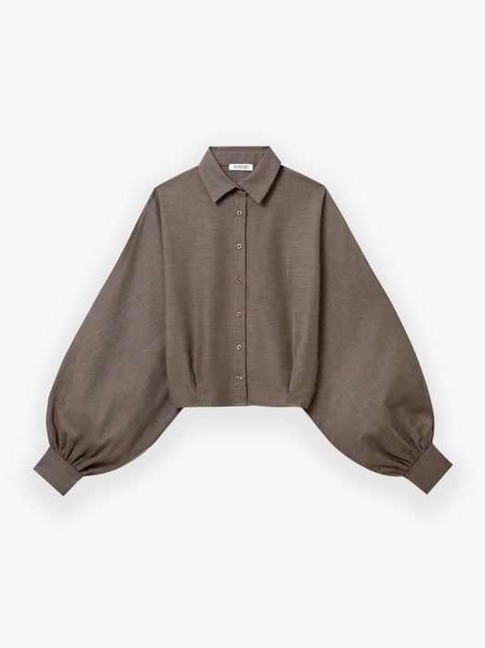 Die Bluse Antonia Short Taupe Flanell ist eine braune, langärmelige Flanellbluse mit Rundhalsausschnitt, Knopfleiste und übergroßen, an breiten Manschetten gerafften Ballonärmeln aus hochwertiger Baumwolle auf weißem Grund.