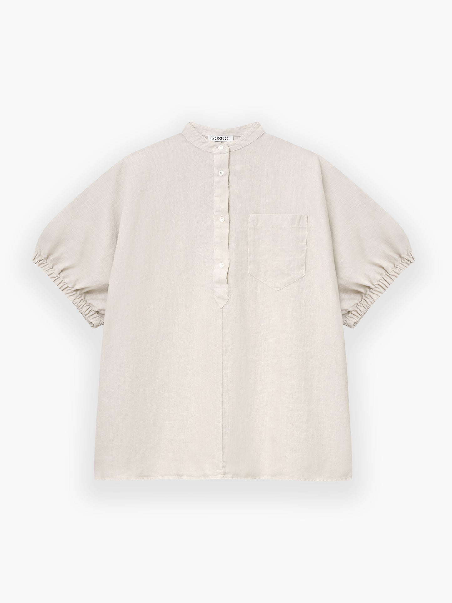 Das Cowboy Button Linen Beige ist ein locker sitzendes, hellbeiges Kurzarmhemd mit Mandarinenkragen, Teilknopfleiste, Brusttasche und gerafften Ärmelsäumen auf weißem Grund.