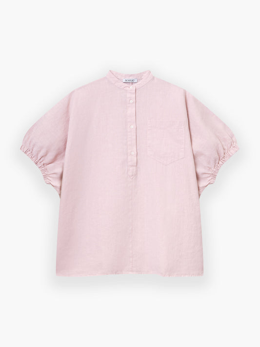 Das Cowboy Button Linen Blush ist ein hellrosa, locker geschnittenes Hemd mit kurzen Ärmeln, Stehkragen, halber Knopfleiste, einer Brusttasche und elastischen Ärmelbündchen.