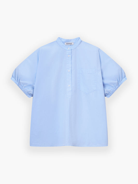 Das Cowboy Button Leinenhemd in Hellblau hat kurze Ärmel, einen Stehkragen, eine halbe Knopfleiste, eine einzelne Brusttasche und eine leicht lockere Passform, dargestellt auf weißem Hintergrund.