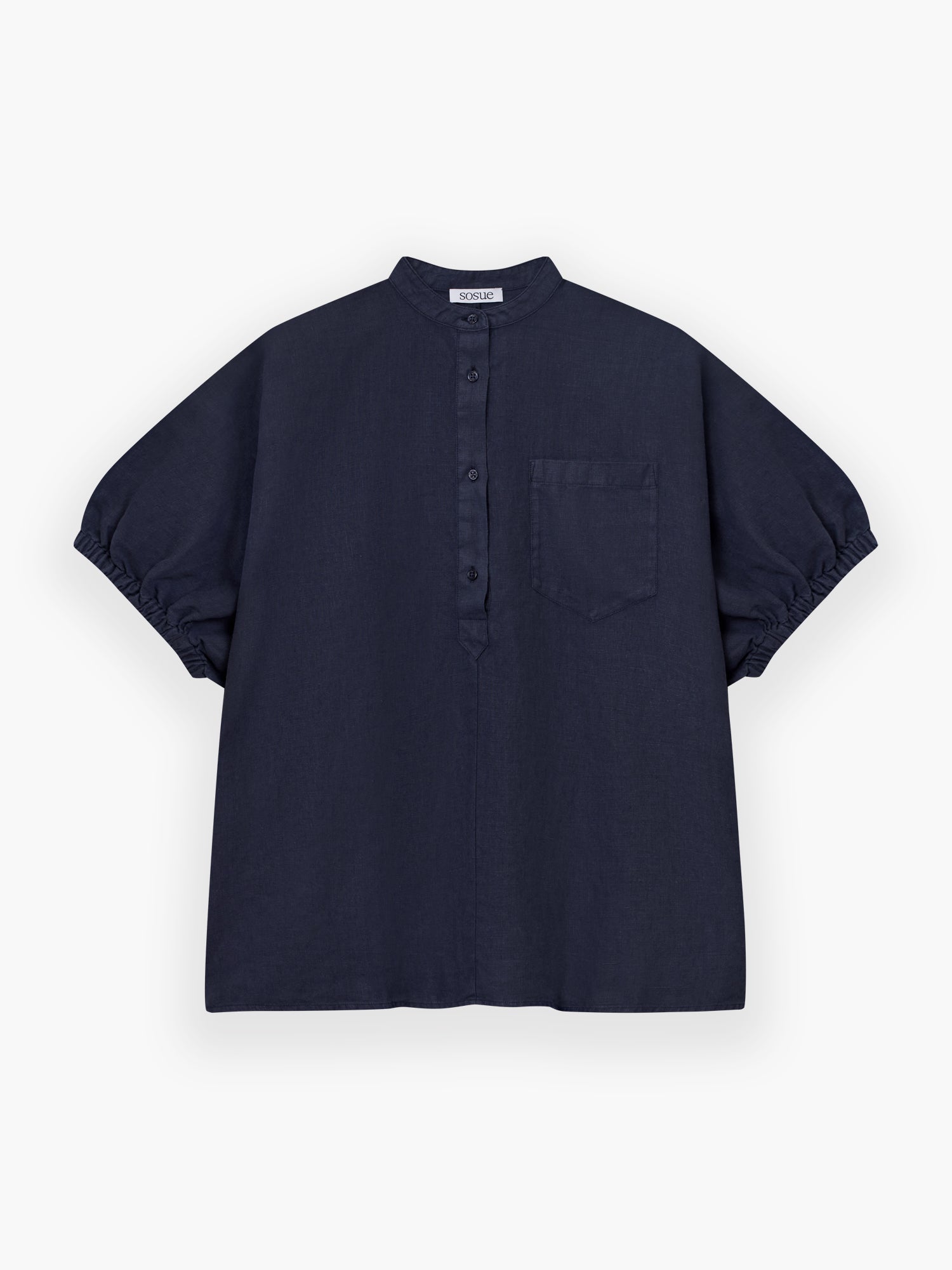 Das Cowboy Button Linen Navy ist ein kurzärmeliges, locker sitzendes marineblaues Hemd mit Mandarinenkragen, Knöpfen vorne, einer Brusttasche und gerafften Ärmeln. Es ist flach auf einem weißen Hintergrund abgebildet.