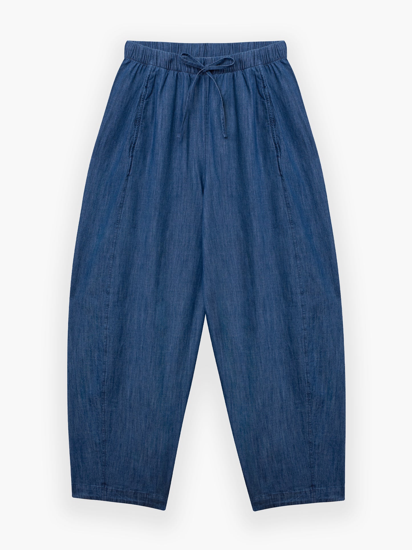 Die Lizzy Denim Hose ist locker geschnitten, hat einen elastischen Bund mit Kordelzug und ist aus leichtem Denim gefertigt. Diese übergroße Hose mit weitem Bein ist flach auf weißem Grund abgebildet.
