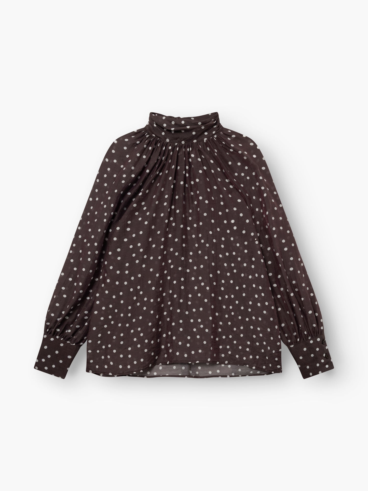 Die Bluse „Dotty Bow Brown Ecru“ ist eine langärmelige, dunkelbraune Bluse mit weißen Punkten, einem hoch gerafften Ausschnitt und Puffärmeln. Sie besteht aus weichem Baumwollvoile und wird flach auf einem weißen Hintergrund abgebildet.