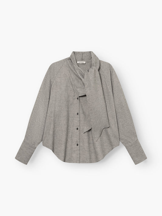Die Bluse „Scarf Tweed“ in Hellgrau verfügt über lange Ärmel, eine Knopfleiste vorne und ein fest eingenähtes Schal-Detail, das locker um den Kragen drapiert ist; abgebildet auf weißem Hintergrund.