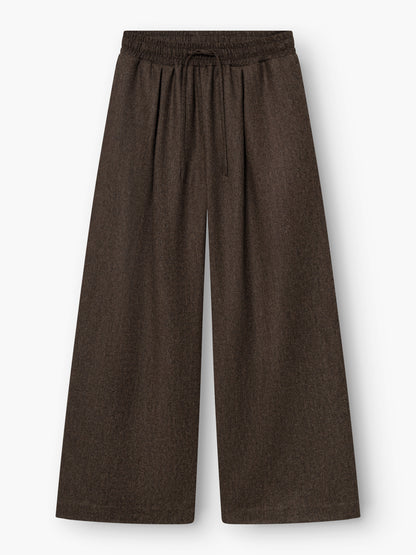 Weit geschnittene Hose „Josy Braun“ mit hoher Taille aus einer dunkelbraunen Wollmischung, mit elastischem Bund und Kordelzug, flach auf weißem Hintergrund präsentiert. Diese stilvolle braune Damenhose wird in Portugal fachmännisch gefertigt und überzeugt durch außergewöhnliche Qualität und Tragekomfort.