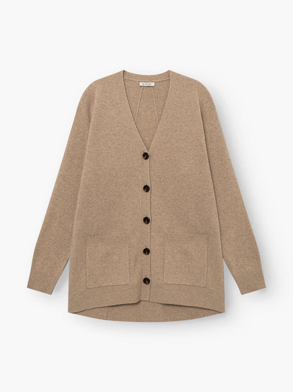 Strickjacke „Lucia Beige“ aus extrafeiner Merinowolle mit langen Ärmeln, schwarzen Knöpfen und zwei Vordertaschen, flach auf weißem Hintergrund präsentiert.