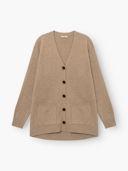 Strickjacke „Lucia Beige“ aus extrafeiner Merinowolle mit langen Ärmeln, schwarzen Knöpfen und zwei Vordertaschen, flach auf weißem Hintergrund präsentiert.