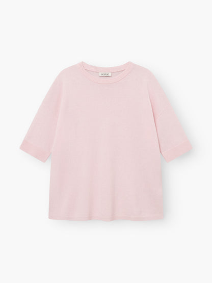 Strick-T-Shirt „Aurora Rose“ in Hellrosa mit kurzen Ärmeln, Rundhalsausschnitt, lockerer Passform und gerippten Säumen an Ärmeln und Saum. Das sichtbare Etikett am Halsausschnitt ist zu sehen, während das Oberteil flach auf einem weißen Hintergrund liegt.