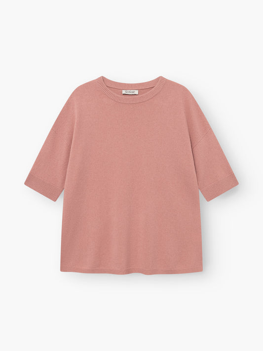 Das Strick-T-Shirt „Aurora Altrosa“ in Blush-Pink liegt flach auf einem weißen Hintergrund. Dieses Damen-Strick-T-Shirt hat kurze Ärmel, einen Rundhalsausschnitt und eine lockere, kastenförmige Passform mit gerippten Säumen an den Ärmelenden, am Saum und am Kragen.