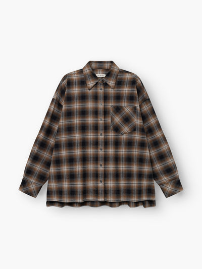 Die „Bluse Boxy Check Long“ ist ein langärmeliges, geknöpftes Oversize-Flanellhemd mit einem karierten Muster in Braun, Schwarz und Beige sowie einer Brusttasche, flach auf einem weißen Hintergrund dargestellt. Dieses Baumwollhemd bietet sowohl Tragekomfort als auch zeitlosen Stil.