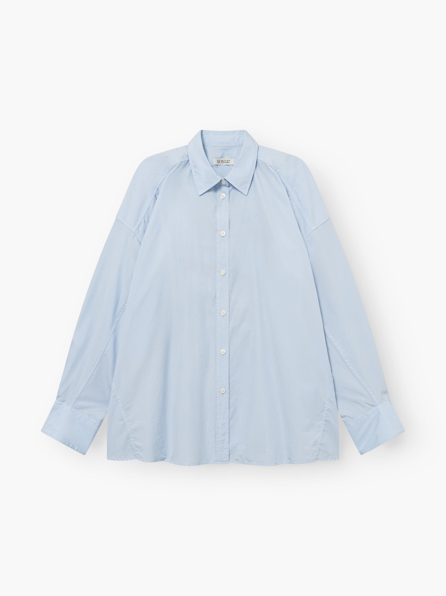 Die Bluse „Hannah Lightblue“ ist ein hellblaues, langärmeliges Oberteil mit Kragen und Knopfleiste in Oversize-Passform sowie weißen Knöpfen auf der Vorderseite, das flach auf einem weißen Hintergrund abgebildet ist.