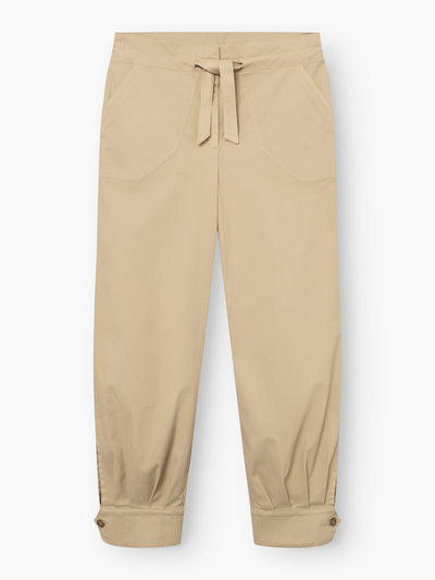 Beigefarbene „Love Pants“ mit Vordertaschen, einem Kordelzug am Bund und geknöpften Bündchen an den Knöcheln, flach auf einem weißen Hintergrund liegend.