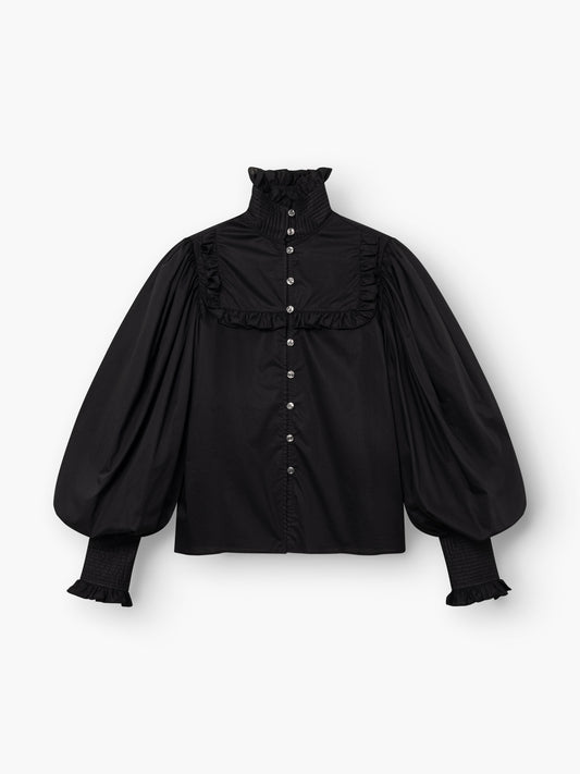 Die Bluse „Victoria“ ist eine schwarze Bluse mit hohem Rüschenkragen, langen Puffärmeln, Rüschendetails, Manschetten und einer Knopfleiste – für einen Hauch viktorianischer Eleganz.