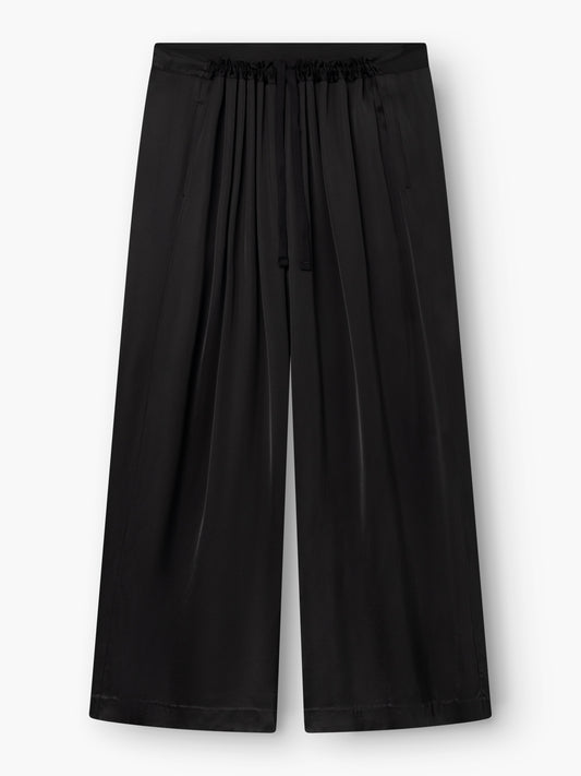 Die schwarze Oversize-Hose besticht durch einen leichten, glänzenden Stoff und einen bequemen, elastischen Bund mit Kordelzug. Diese schwarze Hose hat ein lockeres, fließendes, weit geschnittenes Bein und ist im Taillenbereich mit Falten verziert, die für einen zusätzlichen stilvollen Akzent sorgen.