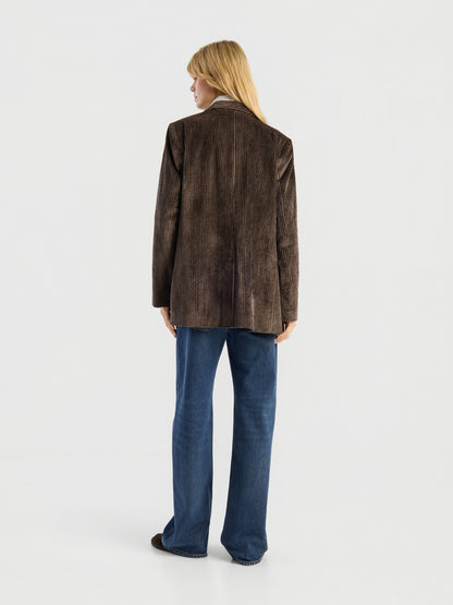 Eine Person steht mit dem Rücken zur Kamera und trägt den Blazer „Alice“ aus braunem Cord sowie eine blaue Jeans. Der Hintergrund ist einfarbig weiß.