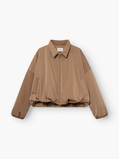 Die „Ballon Jacket“ ist eine hellbraune, langärmelige, kurz geschnittene Jacke mit Reißverschluss vorne, Hemdkragen, Seitentaschen und elastischem Saum, die flach auf einem weißen Hintergrund abgebildet ist.