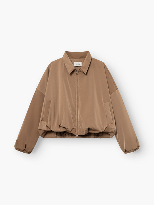 Die „Ballon Jacket“ ist eine hellbraune, langärmelige, kurz geschnittene Jacke mit Reißverschluss vorne, Hemdkragen, Seitentaschen und elastischem Saum, die flach auf einem weißen Hintergrund abgebildet ist.