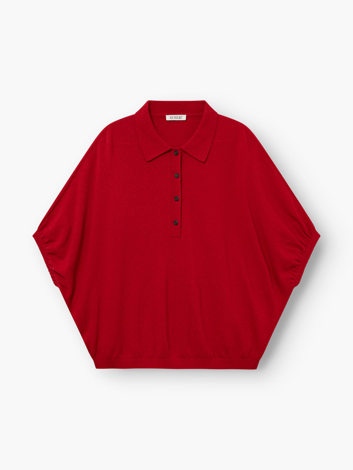 Das „Cowboy Polo Knit Red“ ist ein locker sitzendes, kurzärmeliges Polohemd mit spitzem Kragen und fünf schwarzen Knöpfen auf der Vorderseite, abgebildet auf einem schlichten weißen Hintergrund.