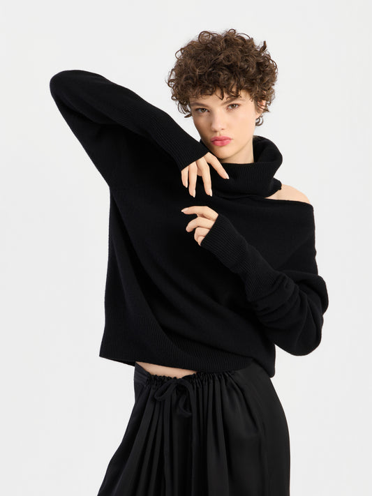 Eine Person, die The Art of Asymmetry trägt, einen schwarzen, schulterfreien Rollkragenpullover mit ausgeschnittenem Ausschnitt.