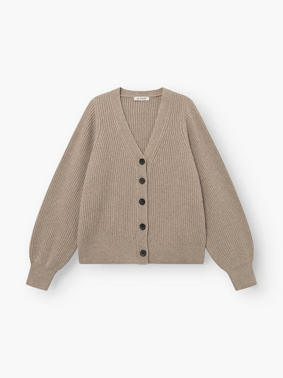Die Strickjacke „Antonia Rib Beige“ ist eine beigefarbene Strickjacke mit Rippmuster, langen Ärmeln, einem V-Ausschnitt und schwarzen Knöpfen an der Vorderseite. Sie zeichnet sich durch eine klassische Rippstruktur aus und wird vor weißem Hintergrund gezeigt.